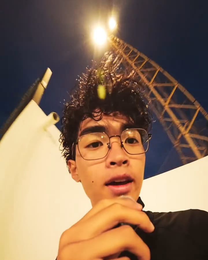 Ziyang habla a cámara de noche junto a las torres de luz de un campo de fútbol