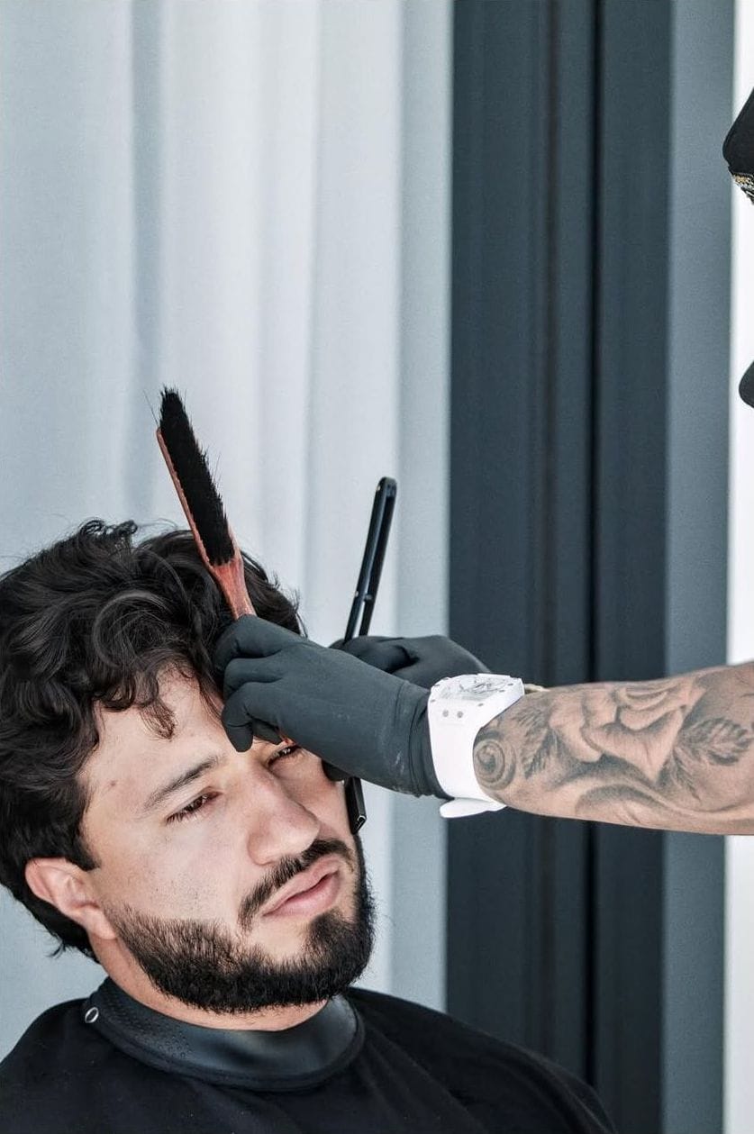 Barbero perfila la barba de un cliente con un peine