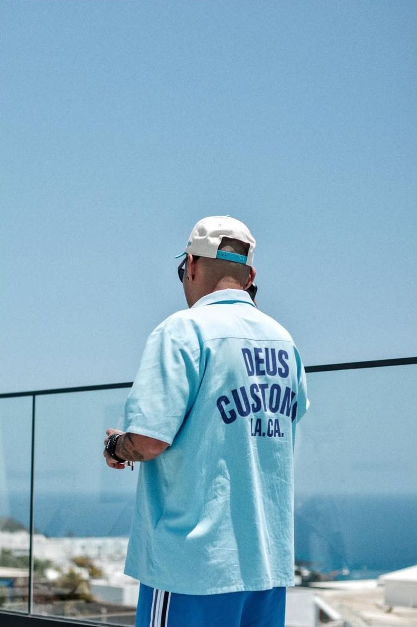 Hombre de espaldas con camisa azul mira al mar