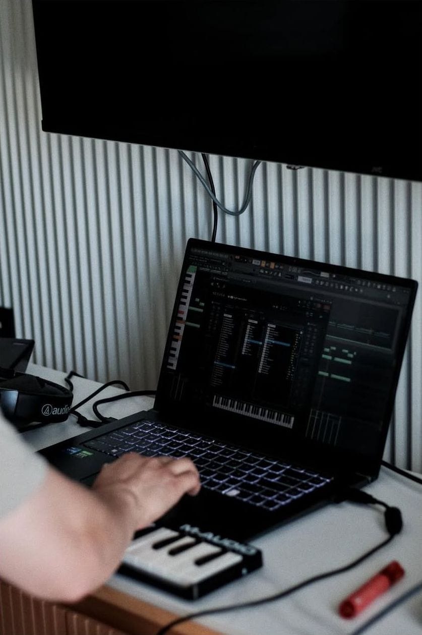 Manos sobre un teclado MIDI junto a un portátil