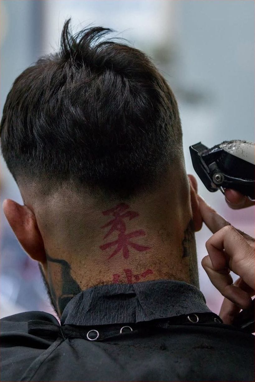Máquina de corte sobre una nuca con un carácter chino tatuado