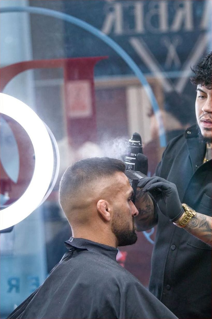 Barbero peina a un cliente junto a un aro de luz