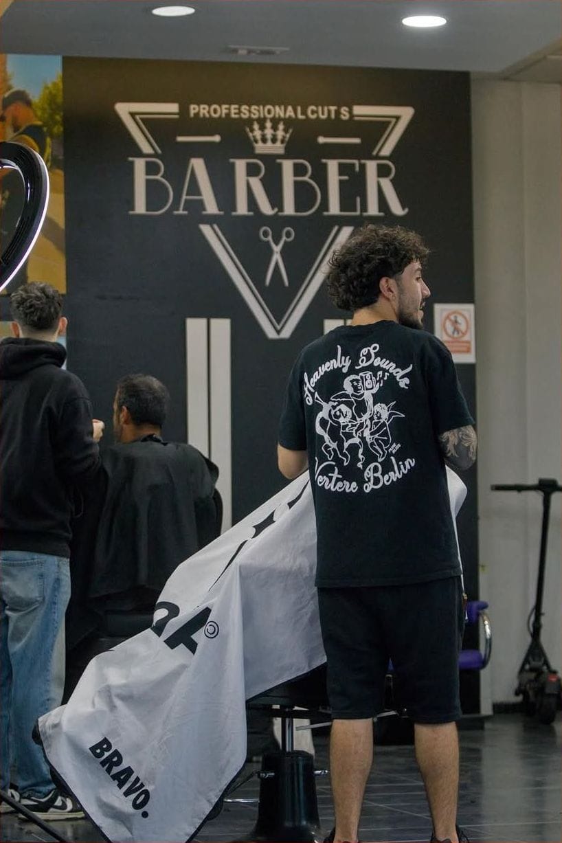 Barbero de espaldas frente al rótulo BARBER de la barbería