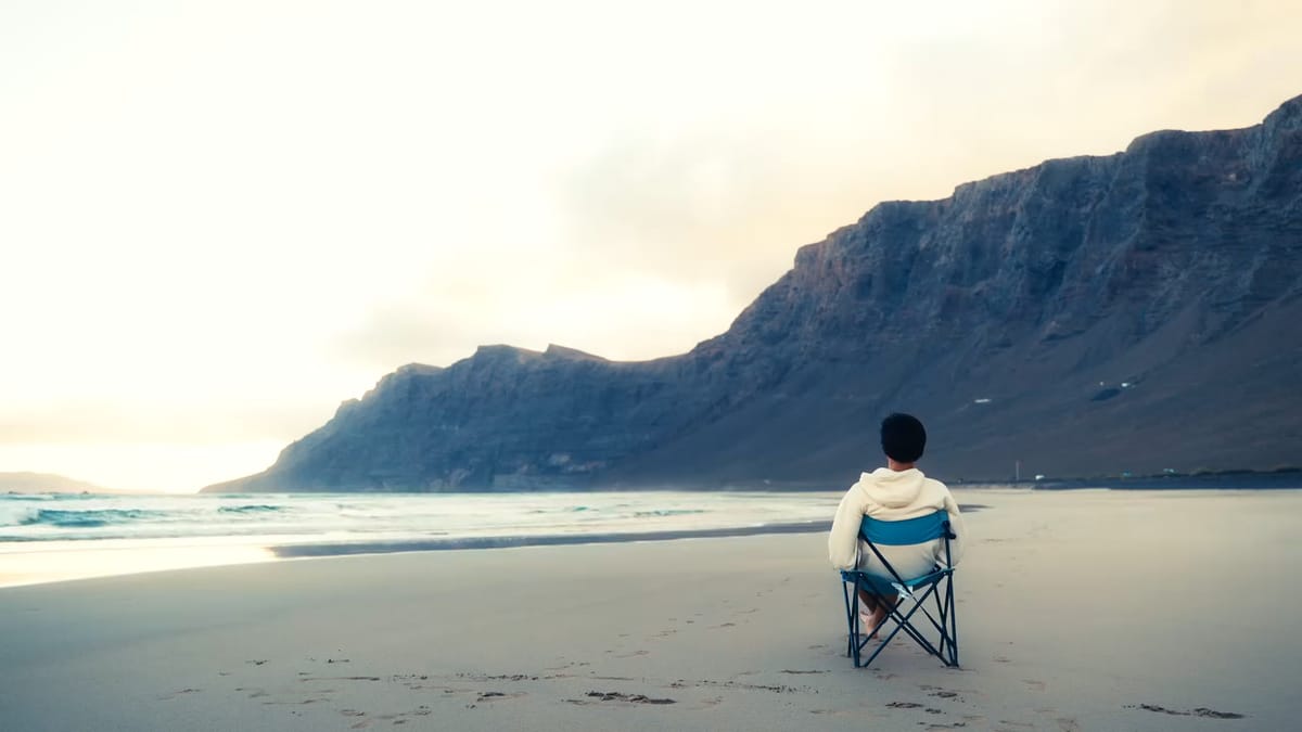 Persona sentada en una silla de playa frente al risco de Famara