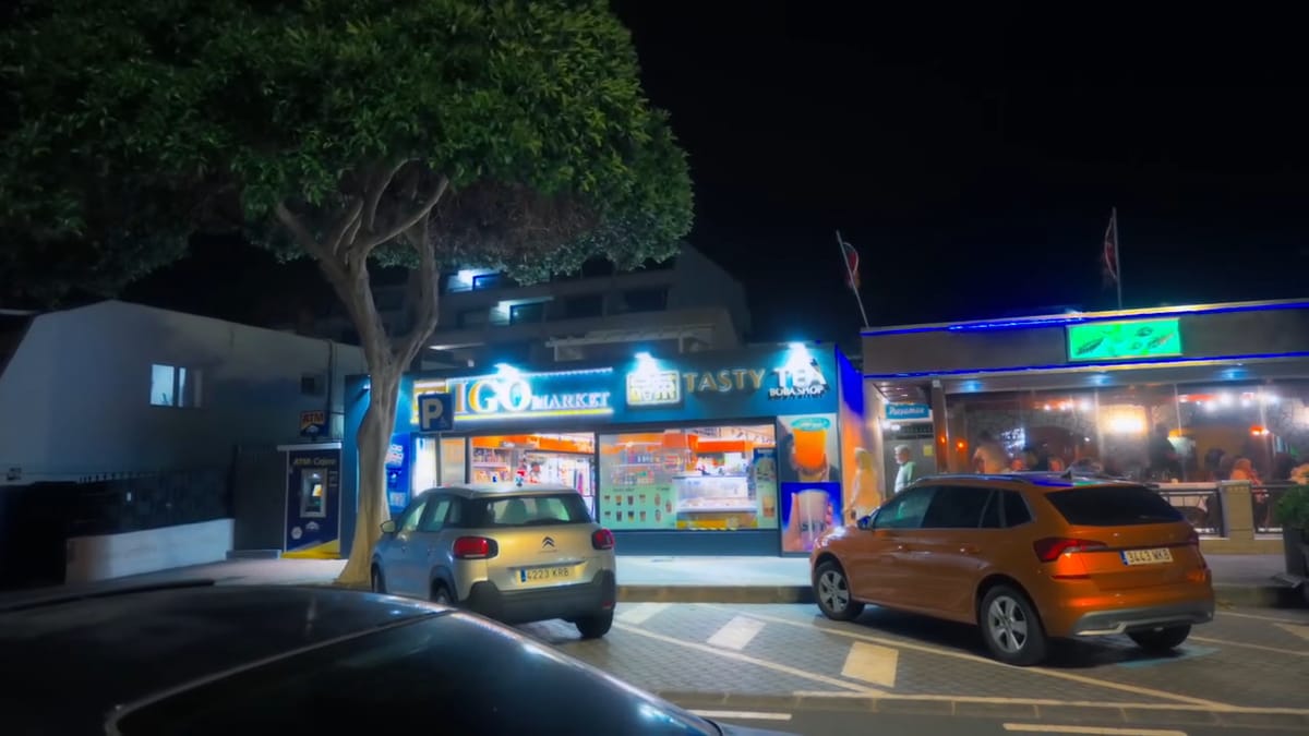 Calle de Puerto del Carmen de noche con coches aparcados y los neones de los locales