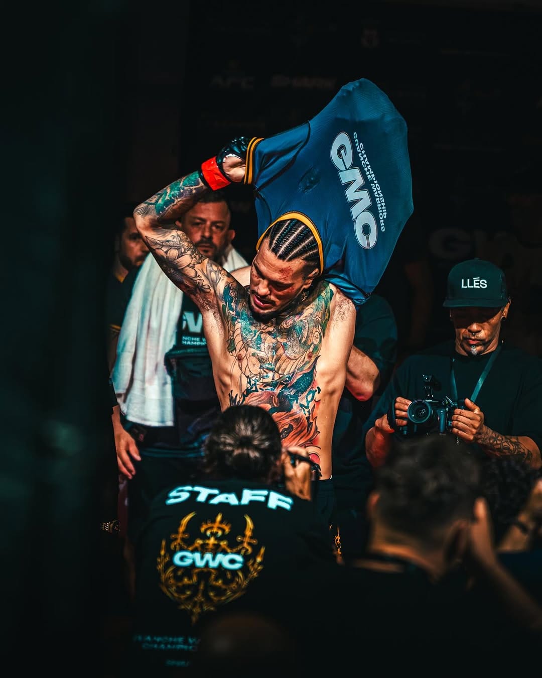 Peleador tatuado camina hacia la jaula rodeado por el staff del evento