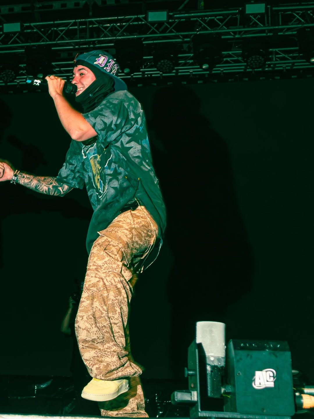 Artista con chaqueta de camuflaje rapea en el escenario