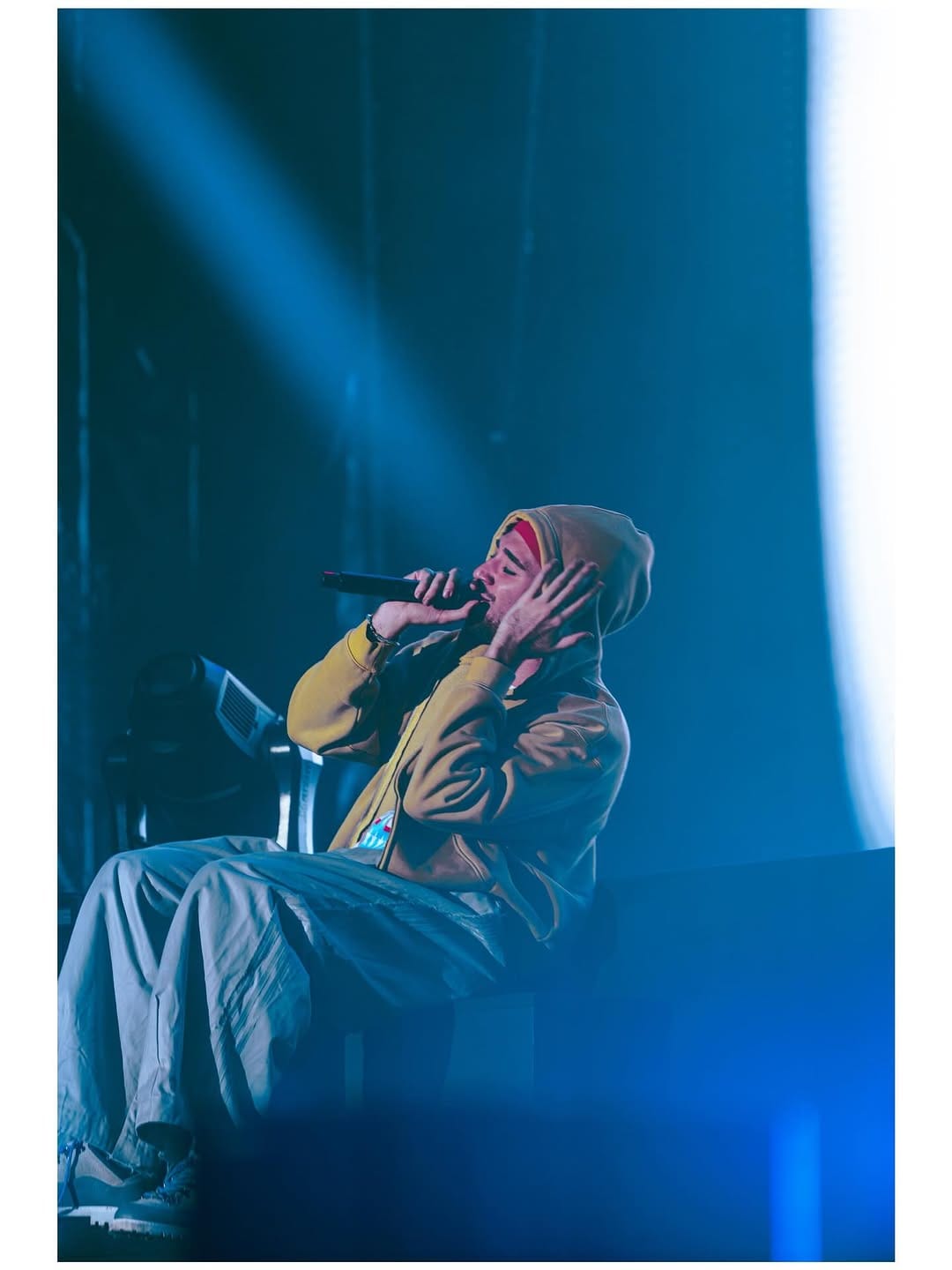 Artista sentado en el escenario bajo un foco azul