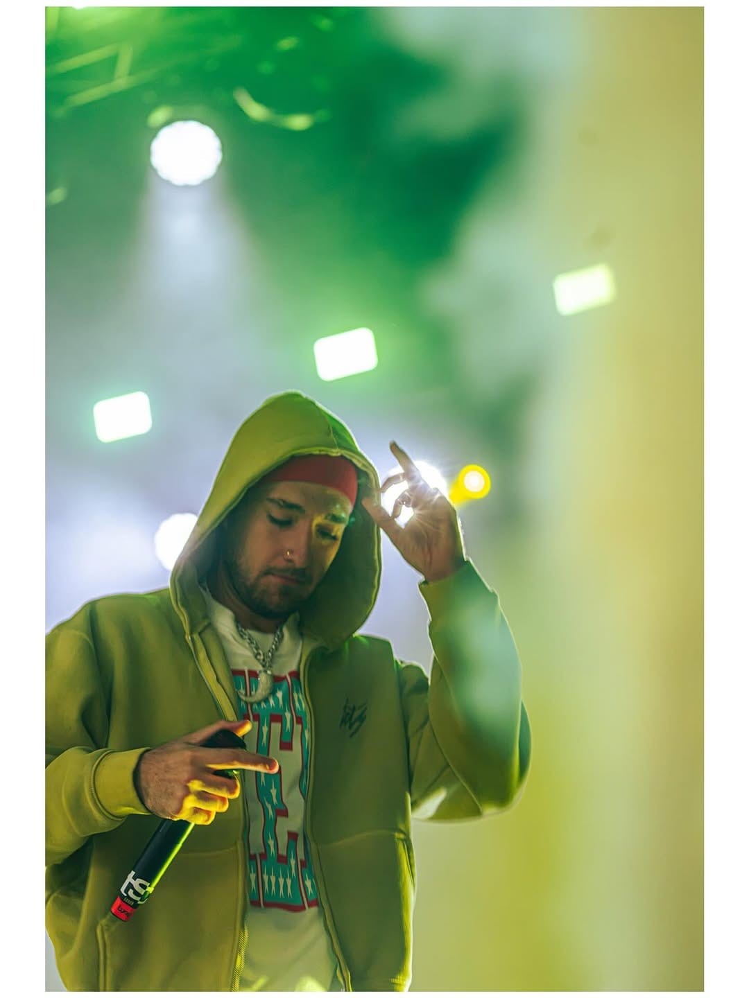 Artista con capucha amarilla bajo focos verdes