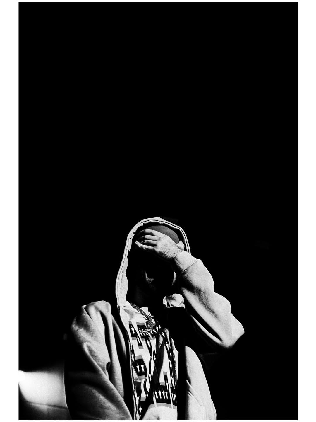 Artista con capucha en blanco y negro sobre fondo negro