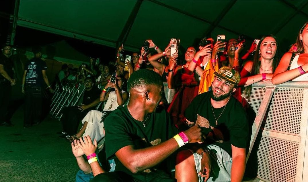 Público en la valla del festival, con dos personas sentadas en primera fila