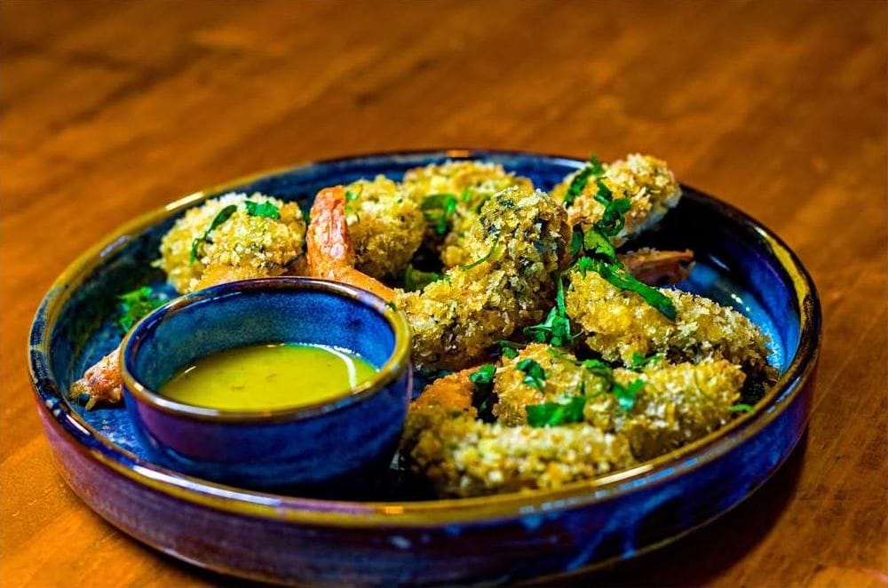 Langostinos rebozados con salsa en un plato azul