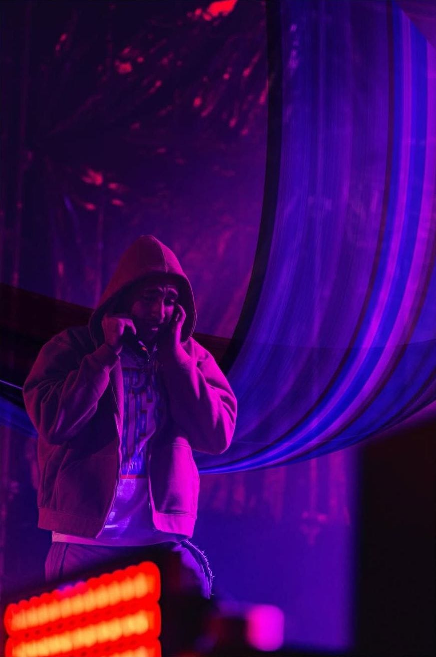 Artista con capucha bajo luz violeta con bandas de píxeles