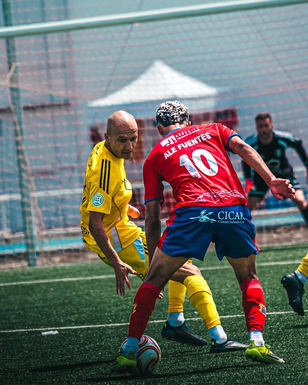 Alf Fuentes, dorsal 10 de la UD Lanzarote, protege el balón ante un defensor de amarillo